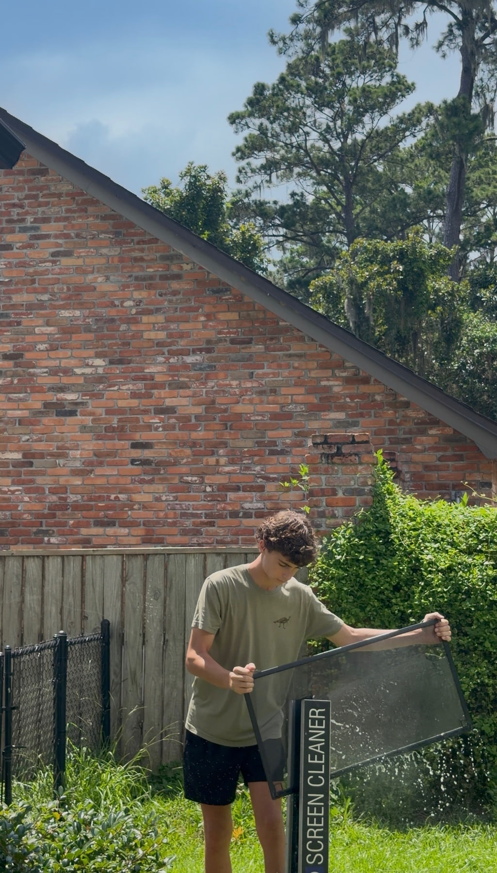Brooks Safley cleaning a window screen outside a Tallahassee home.